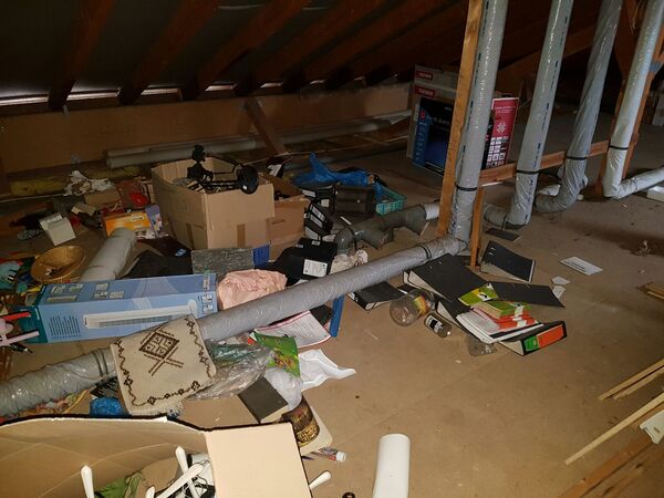 Unaufgeräumter Dachboden mit Kartons, alten Aktenordnern, Rohren und verschiedenen Gegenständen.