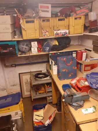Kellerraum mit Werkbank, Werkzeug, Regalen, Archivboxen und gelben Lagerkisten.